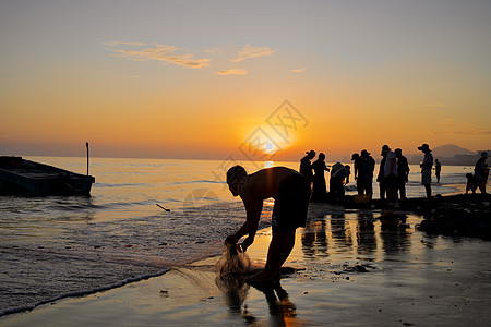 夏天海边夕阳下捕鱼的人图片