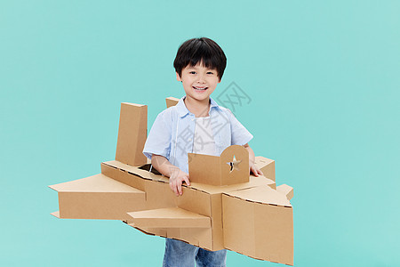 身穿纸板飞机模型玩耍的小男孩图片