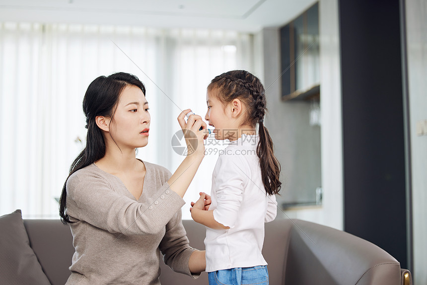 母亲给生病的女儿使用哮喘喷雾图片