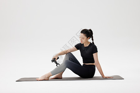 拉伸动作健身女性使用筋膜枪放松腿部肌肉背景