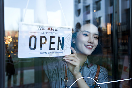 生活热情咖啡店的女服务员挂营业标志背景