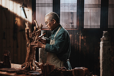 眼镜制作工艺在树根上认真雕刻的工匠师背景