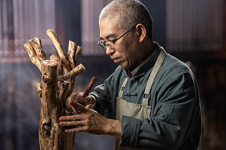 眼镜制作工艺在树根上认真雕刻的工匠师背景