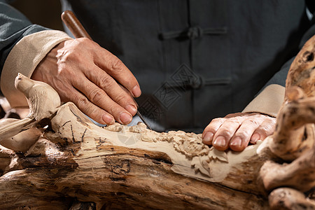 木匠雕刻工具工匠师在树根上雕刻背景