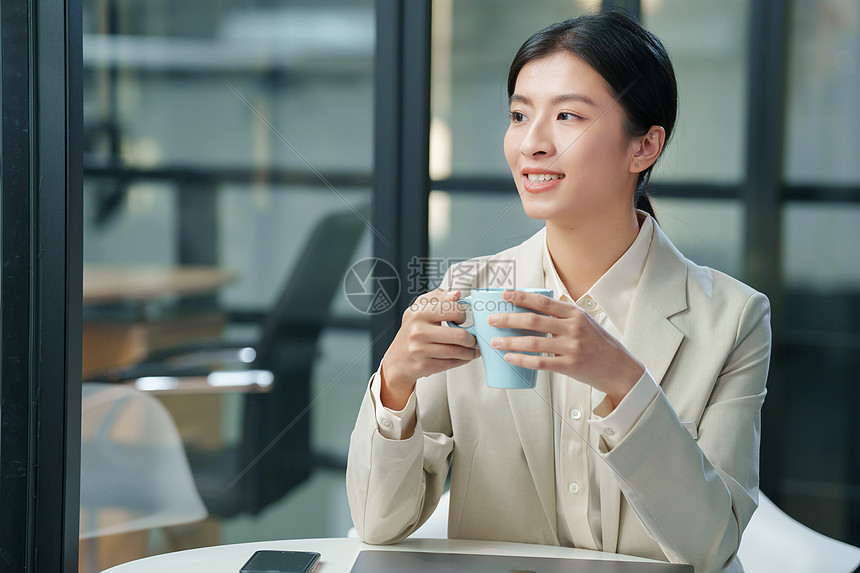 青年商务女士坐在办公室里喝水图片