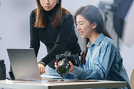 在拍照的人在工作室里讨论工作的青年女摄影师背景