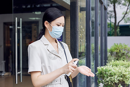 抗菌防霾口罩戴口罩的商务女青年手拿消毒喷雾背景