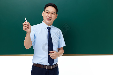 中年男教师手拿粉笔站在黑板前授课图片