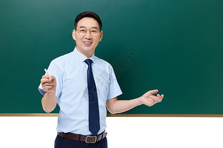 男老师手拿粉笔站在黑板前讲课图片