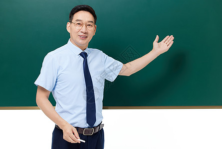 男教师手拿粉笔站在黑板前授课图片