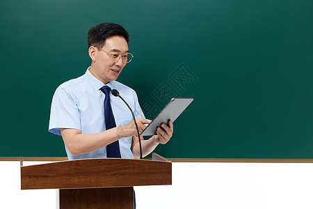 男教授手拿平板电脑在讲台上讲课图片