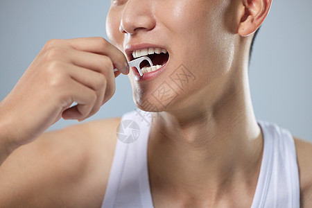 男性口腔护理年轻男性使用牙线清洁牙齿特写背景