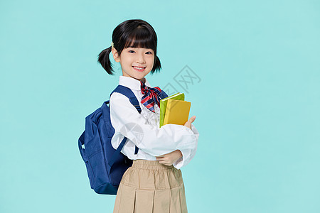 抱着书的小女孩抱着书本背书包上学的小女孩背景