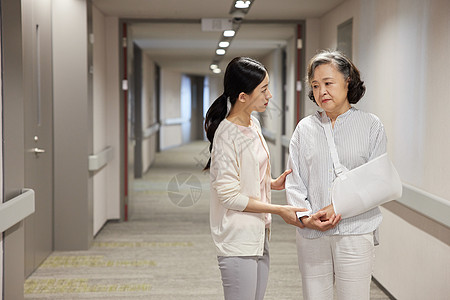医院走廊上青年女性搀扶骨折的老人高清图片