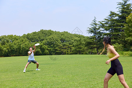 青年男女在户外公园玩飞盘图片