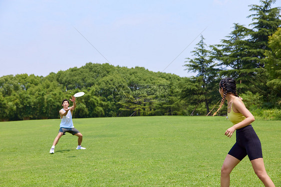 青年男女在户外公园玩飞盘图片