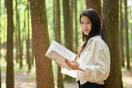 森系迎宾牌在树林里看书休闲的美女背景