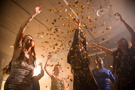 一群美丽的年轻女子在金彩蛋白浴下跳舞享受夜总会的狂欢图片