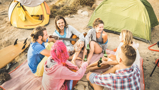 朋友们在海滩露营派对上玩得开心快乐的友谊旅行概念与年轻人在夏季冲浪营弹吉他和喝瓶装啤酒温暖图片