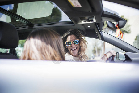 年轻美丽的女士们在汽车中笑图片