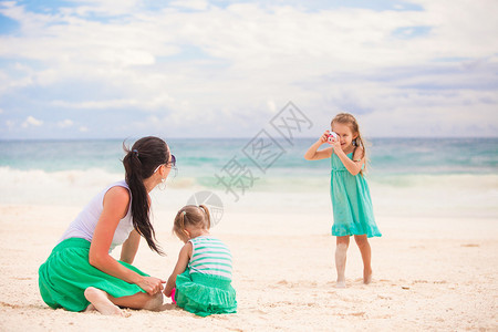 懂事的小女孩在沙滩上给妈妈和妹妹拍照片图片