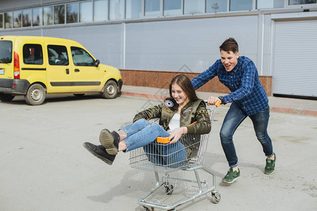 青少年在街上玩得开心在购物车里骑车图片