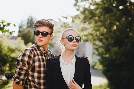 特写时尚肖像的年轻夫妇在城市街头摆在夏季风格的衣服复古太阳镜时尚夫妇在太阳镜时尚服装秋季衣服背景图片