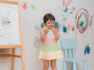 一个3岁的小女孩在她房间的墙上用油漆和刷子画了一个拱形的样子顽皮的孩子背景图片