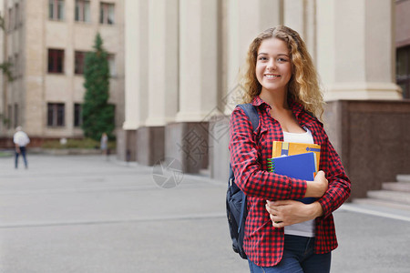 美丽微笑的女学生站在大学校园前图片