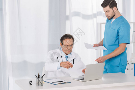 医生阅读文件并将其交给护士图片