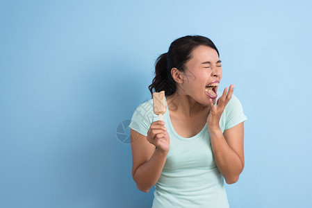 亚洲年轻女牙齿超敏感吃冰棒的亚裔女孩用复制背景图片