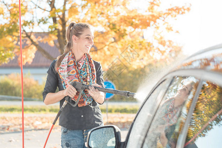 使用高压喷嘴清洁和洗车的妇女图片