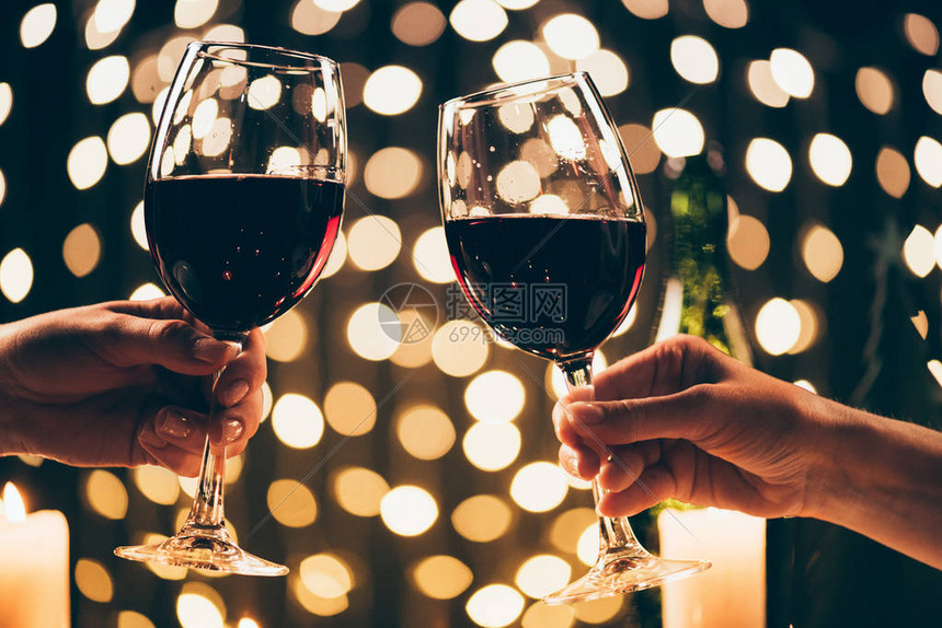 两名女在bokeh面前用红葡萄酒和杯子连结玻