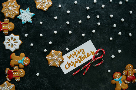 黑桌牌上自制姜饼糖果甘蔗和圣诞快乐贺背景