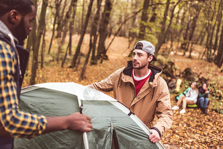 青年男子在秋林中安营扎帐篷女孩高清图片