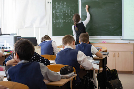 女孩少年女学生上课时在教室的黑板上写字教育培训儿童保育后视图图片