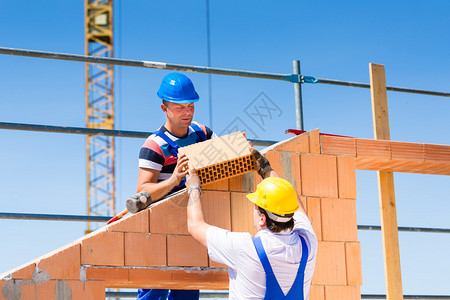 两名瓦工或建筑工人或工人在建筑或建筑工地上建造或砌砖或铺图片