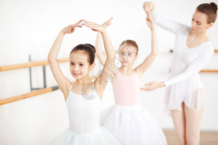 小芭蕾舞小芭蕾女伴手举起头来跳舞而老师背景图片