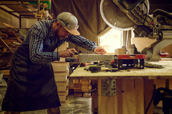 身着工作服的经验丰富的木匠和在木工车间工作的小企业主图片