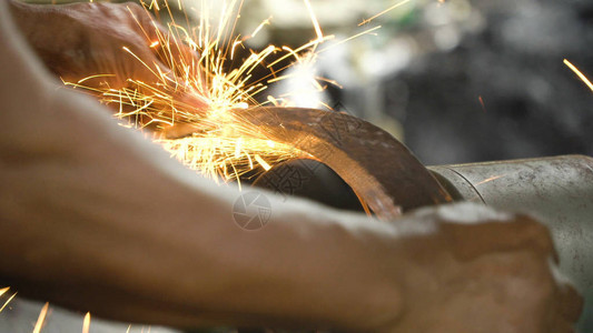 在铁匠铺的磨刀机上磨刀磨刀器和带刀片的手工人用磨石图片