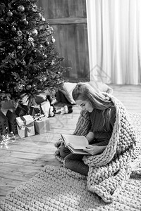 坐在地毯上在圣诞节读书拍黑白照片的有想象背景图片