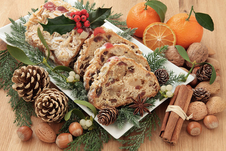 Stollen圣诞蛋糕与冬青橘子坚果香料和冬季绿色植图片
