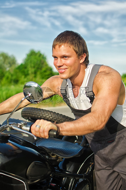 英俊的机械师推着摩托车的画像图片