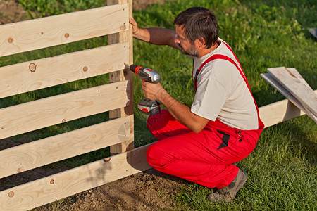 建造木栅栏的人用螺丝固定木板图片