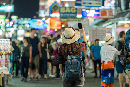 泰国曼谷夜间在考山路步行街拍照的亚洲年轻旅行女背面旅行图片