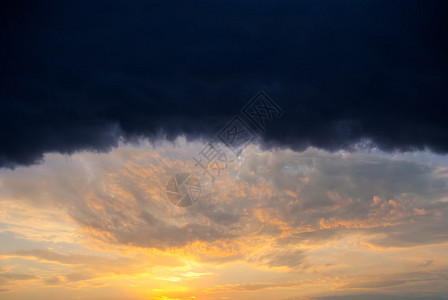 巨大的雨云照亮了橙色的夕阳图片