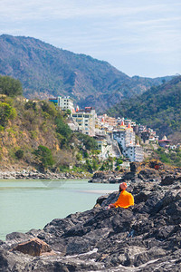 印度圣城和旅游目的地Rishikesh河岸边的橙色佛教僧侣图片