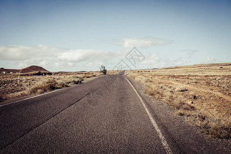 长的黑色沥青路经过沙漠滩图片