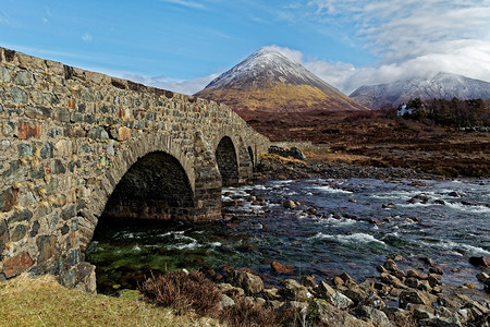 山中宽阔溪流上的旧石桥图片