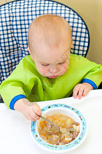 小女孩在高脚椅上用勺子吃饭图片